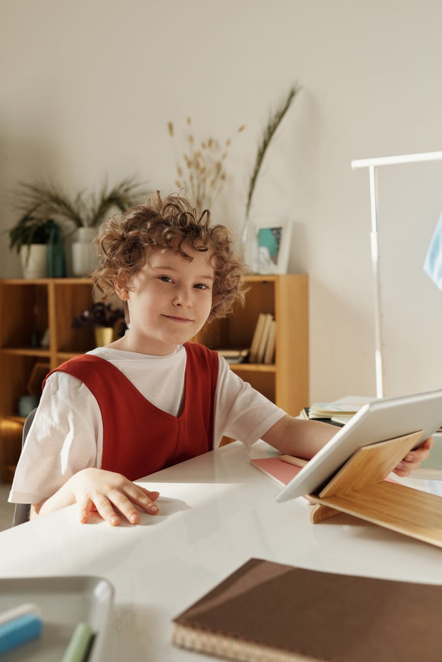 boy sitting by the table while smiling